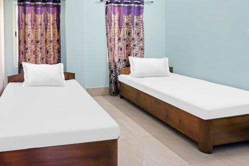 Dos camas una al lado de la otra en una habitación. en Hotel O Rainbow, en Tezpur