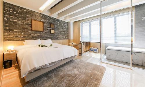 a bedroom with a large bed and a brick wall at Hotel Yeogiuhtte SeoDaegu in Daegu