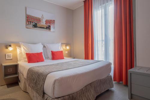 a bedroom with a bed with red curtains and a window at H&ocirc;tel de la Fontaine in Nice