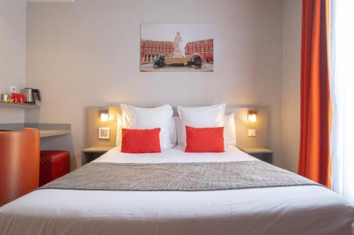 a bedroom with a bed with two red pillows at H&ocirc;tel de la Fontaine in Nice