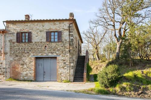 une vieille maison en pierre avec un garage et un arbre dans l'établissement Guest House il Gatto, à Gaiole in Chianti