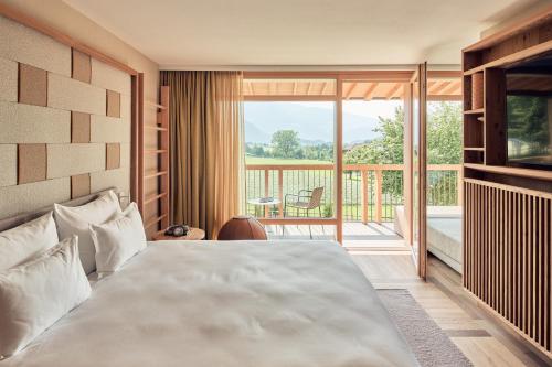 a bedroom with a large bed and a balcony at Falkensteiner Hotel Kronplatz - The Leading Hotels of the World in Brunico