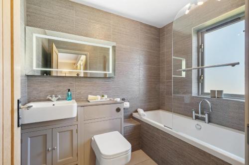 a bathroom with a tub and a sink and a toilet at Oaktree Lodge - Luxury Cottage, Hot Tub, Sea Views in Saundersfoot