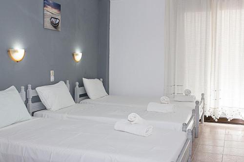 three beds in a room with white towels on them at La Pensione Skiathos in Skiathos