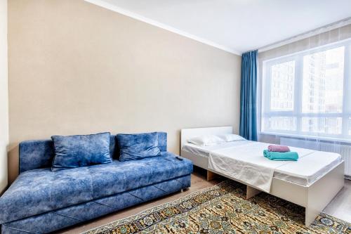 een bed en een bank in een kamer met een raam bij Квартира в центре города 7-й этаж in Taldykolʼ