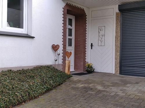 een witte deur met harten aan de zijkant van een huis bij Ferienwohnung Rastplatz in Schmallenberg