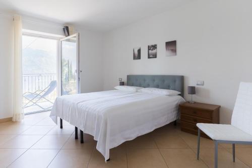 a white bedroom with a bed and a balcony at Appartamenti Ceccherini in Malcesine
