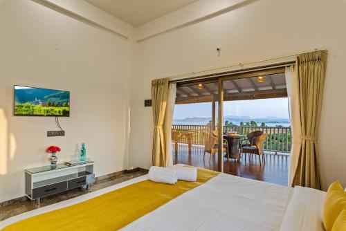 a bedroom with a bed with a television and a balcony at SaffronStays Mango Lakeview Villa, Nashik in Nashik