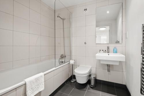 a white bathroom with a sink and a toilet at One Bed Serviced Apartment near Blackfriars in London