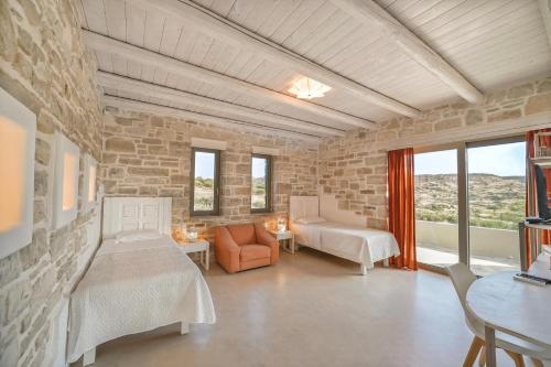a living room with two beds and a stone wall at Beachfront villa Komos with heated pool in Kalamaki