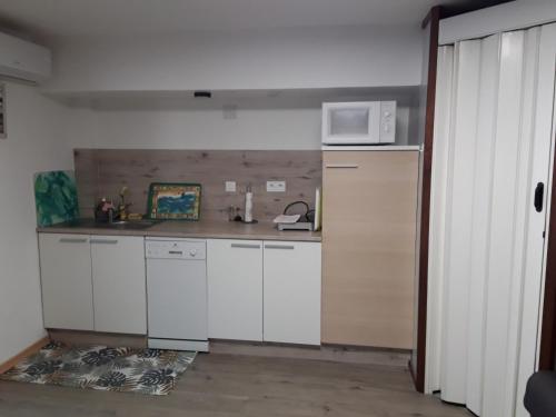 a kitchen with white cabinets and a microwave at Studio cocon in Cabestany