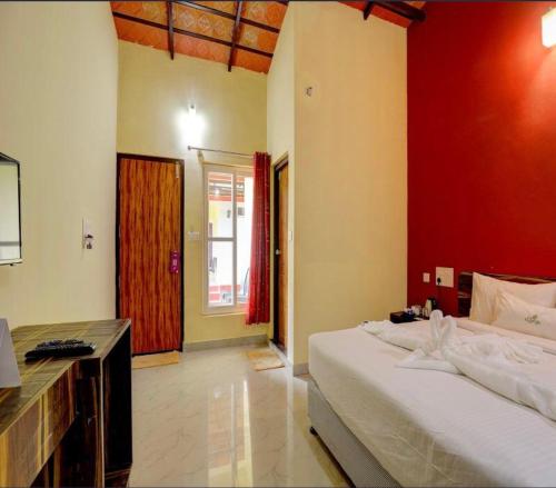 a bedroom with a large bed and a red wall at Lazo Areca Resort , Coorg in Madikeri