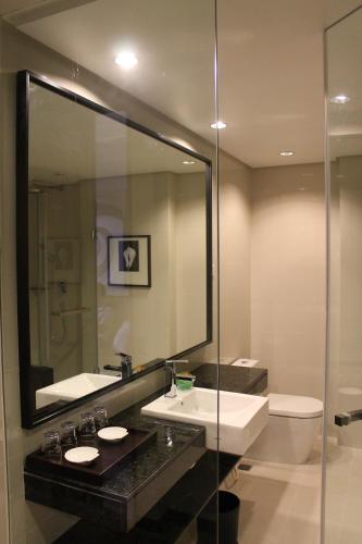 a bathroom with two sinks and a mirror and a toilet at I Hotel Baloi Batam in Nagoya