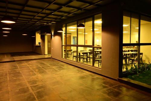 Clarks Inn Express, KRS road-Mandya, Mysore في ميسور: غرفة فارغة فيها طاولات وكراسي ونوافذ