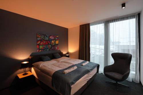 a bedroom with a bed and a chair and a window at Ponton Rooms in Bratislava