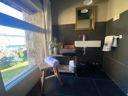 a bathroom with a sink and a chair and a window at Xalet Montana in Ur