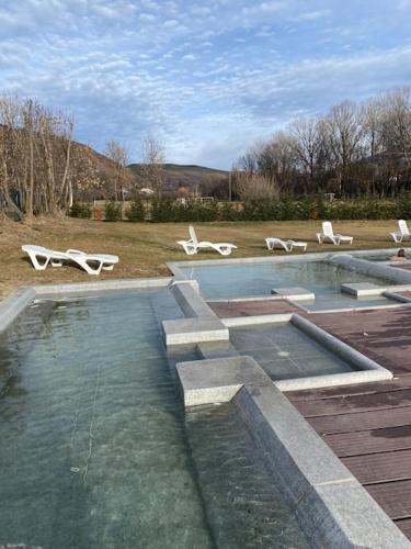 une piscine d'eau avec des chaises blanches dans un champ dans l'établissement Xalet Montana, à Ur