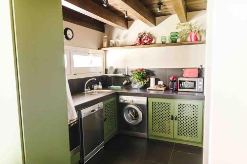 uma cozinha com armários verdes e uma máquina de lavar roupa em Xalet Montana em Ur