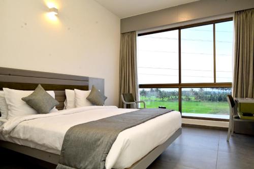 Clarks Inn Express, KRS road-Mandya, Mysore في ميسور: غرفة نوم بسرير كبير ونافذة كبيرة