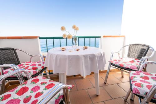 une table blanche avec des chaises et un vase de fleurs. dans l'établissement Apartamento junto al mar en costa tropical y Alpujarras granadinas, à Melicena