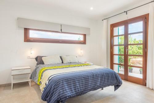 ein weißes Schlafzimmer mit einem Bett und einem Fenster in der Unterkunft Son Vivot by BeBreeze in Inca