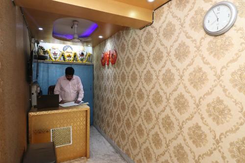 uma pessoa sentada numa secretária com um computador portátil em OYO Hotel Jagannath International Near Kolkata Airport em Gauripur