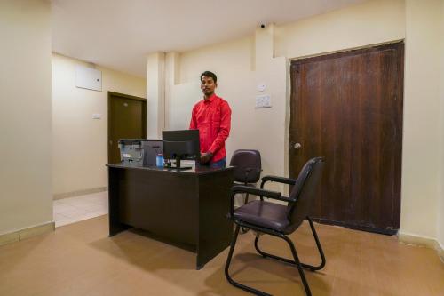 un hombre parado en un escritorio con una computadora en Alpine glow Zenith, en Hyderabad