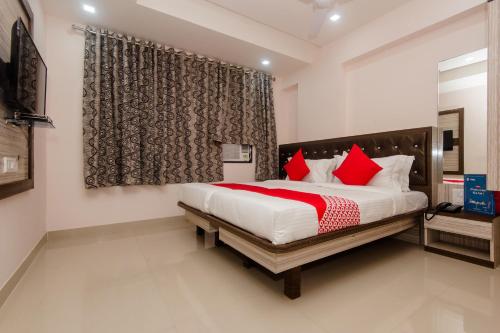 a bedroom with a large bed with red pillows at OYO Hotel Gems in Turambhe