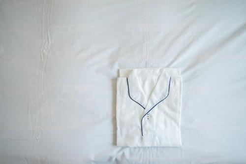 a white shirt hanging on a white bed at Hotel Casabella Inn Kobe in Kobe