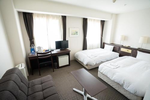 a hotel room with two beds and a desk at Hotel Casabella Inn Kobe in Kobe