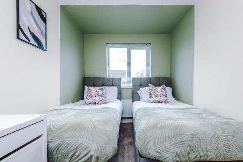 two beds in a room with green walls at Chic 2 Bed House with Garden & Free Parking in Manchester