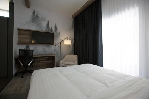 a bedroom with a bed and a tv and a chair at Hotelia in Saint-Ambroise