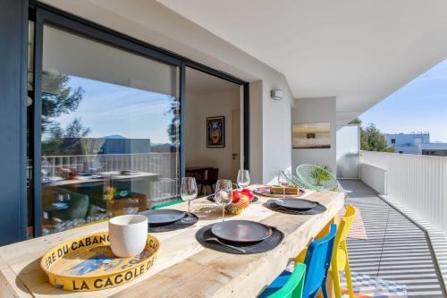 - une salle à manger avec une table en bois et des assiettes dans l'établissement Nice flat with terrace in La Garde near the beach - Welkeys, à La Garde