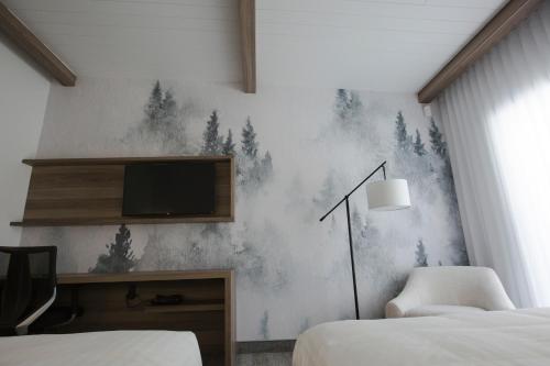 a bedroom with two beds and a tv on a wall at Hotelia in Saint-Ambroise