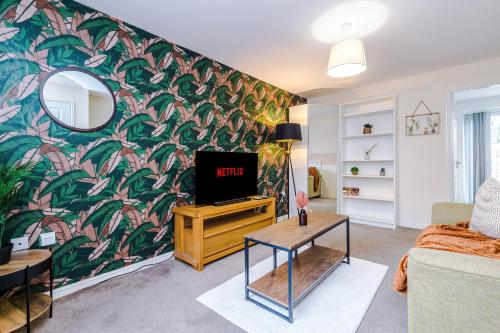 a living room with a tv and a mural at Chic 2 Bed House with Garden & Free Parking in Manchester