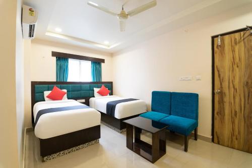 a hotel room with two beds and a chair at Capital O Seatree in Visakhapatnam