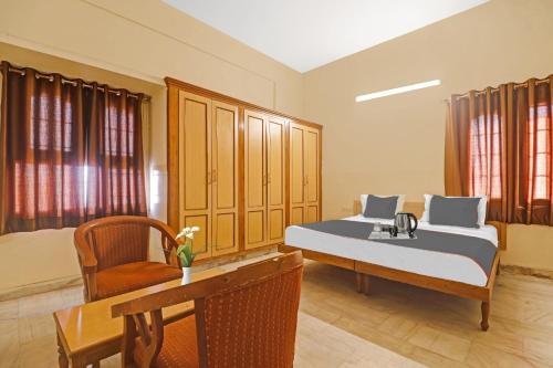 ハイデラバードにあるCapital O Hotel Samrat Palace Near Nampally Stationのベッドルーム1室(ベッド2台、デスク、椅子付)