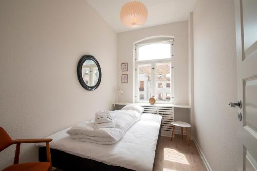 a bedroom with a bed with white sheets and a window at Det Gamle Rådhus in Gråsten