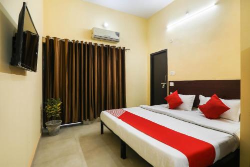 a bedroom with a bed with red pillows and a television at OYO Flagship Laavin Inn Near Gomti Riverfront Park in Hasanganj