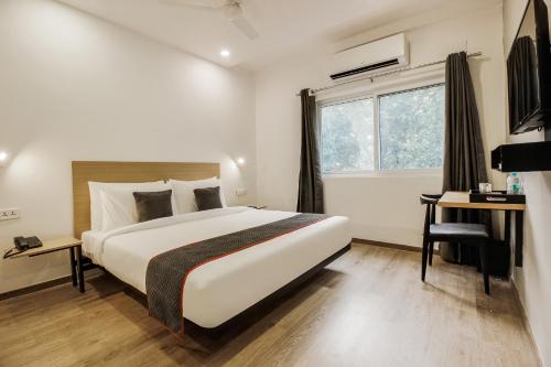 a hotel room with a bed and a desk and a window at Townhouse Begumpet Near Hyderabad Central in Ameerpet