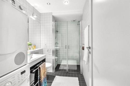 uma casa de banho branca com um chuveiro e um WC. em Tjuvholmen / Aker Brygge - Most expensive area in Oslo! em Oslo