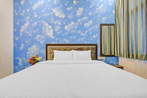 a bedroom with a white bed and a blue wall at Capital O Maharana Palace in Udaipur