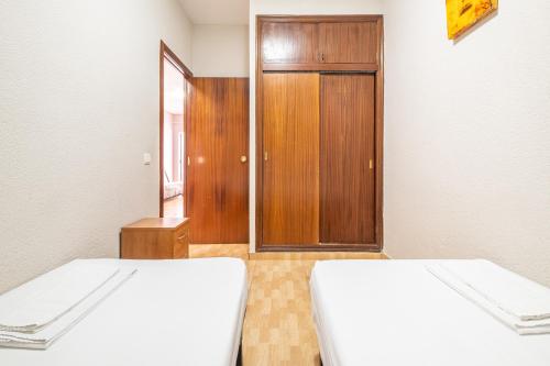 a room with two beds and a wooden door at Apartamentos Lepanto 21 Levante Area in Benidorm