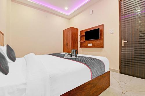 een slaapkamer met een wit bed en een televisie bij Townhouse Kalyanpur Metro in Kaliānpur