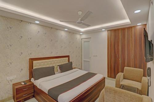 a bedroom with a bed and a chair and a tv at Super Collection O Hotel Spot Light Near Tughlakabad Station Metro Station in Indraprast