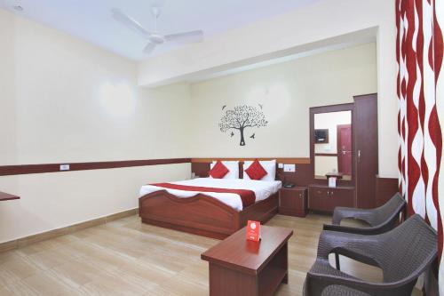 een slaapkamer met een bed, een stoel en een tafel bij Coorg Mandarin in Madikeri