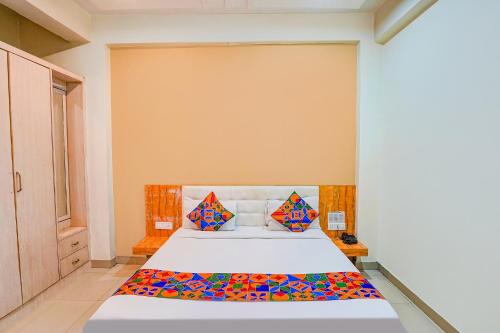 een slaapkamer met een bed met kleurrijke lakens en kussens bij FabHotel Bliss Inn in Prayagraj