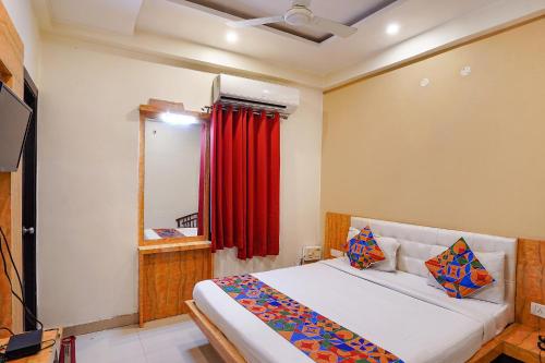 a bedroom with a bed and a red curtain at FabHotel Bliss Inn in Prayagraj
