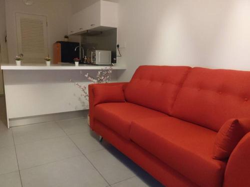 a red couch in a living room with a kitchen at KA1707 - Cyberjaya-Netflix-Wifi- Parking, 1005 in Cyberjaya