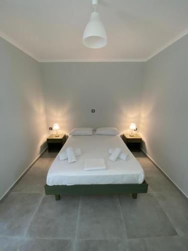 a white bedroom with a bed and two night stands at Dina’s house in Argostoli